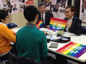 池内候補（右奥）に、当選を祈願する虹色の旗を贈る 後援会メンバー（手前）。左奥は、そねはじめ都議 ＝7日、東京都内