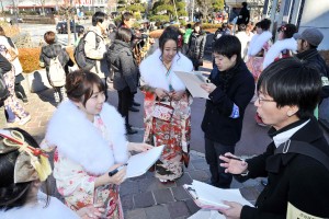 成人式会場前で新成人と対話する民青同盟員＝12日、渋谷区