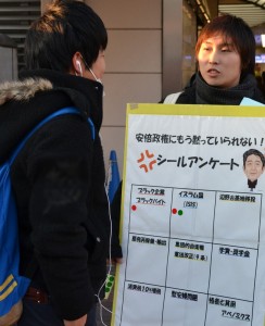 「安倍政権にもう黙っていられない!」のシールアンケートで対話する民青同盟員(右)=12日