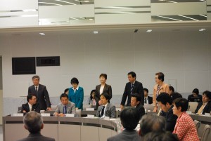 共産党提案の予算組み替え案に賛成して起立する党都議団=25日、東京都議会