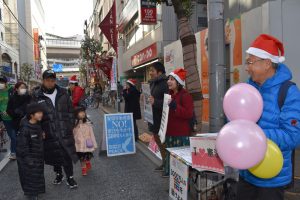サンタの帽子をかぶって「子どもたちに平和を送ろう」と訴える人たち＝24日、世田谷区