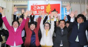 18日深夜、全員当選確定を受けてバンザイをする（左から）清水とし子、ちかざわ美樹、岡田じゅん子、大高哲史、中野あきとの各氏（日野市委員会事務所撮影）